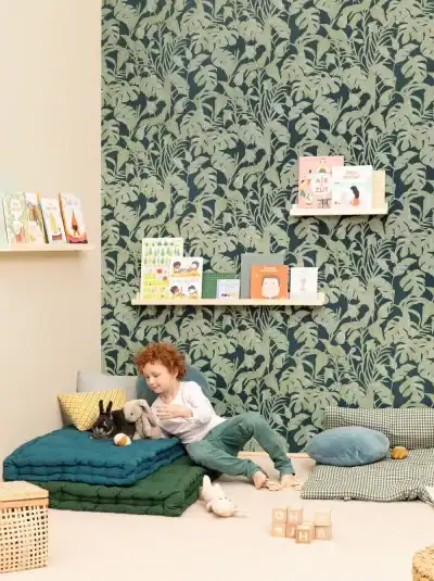 Papier peint uni de la marque Empire, dans une chambre d'enfant avec un motif végétal vert foncé.