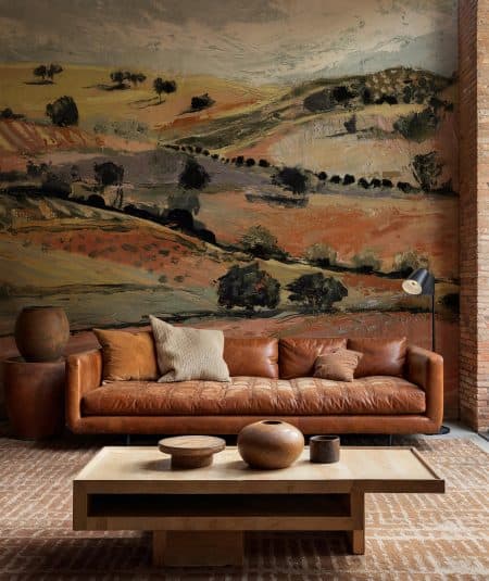Papiers peints Empire Quijote dans un salon avec canapé en cuir et décor mural champêtre.